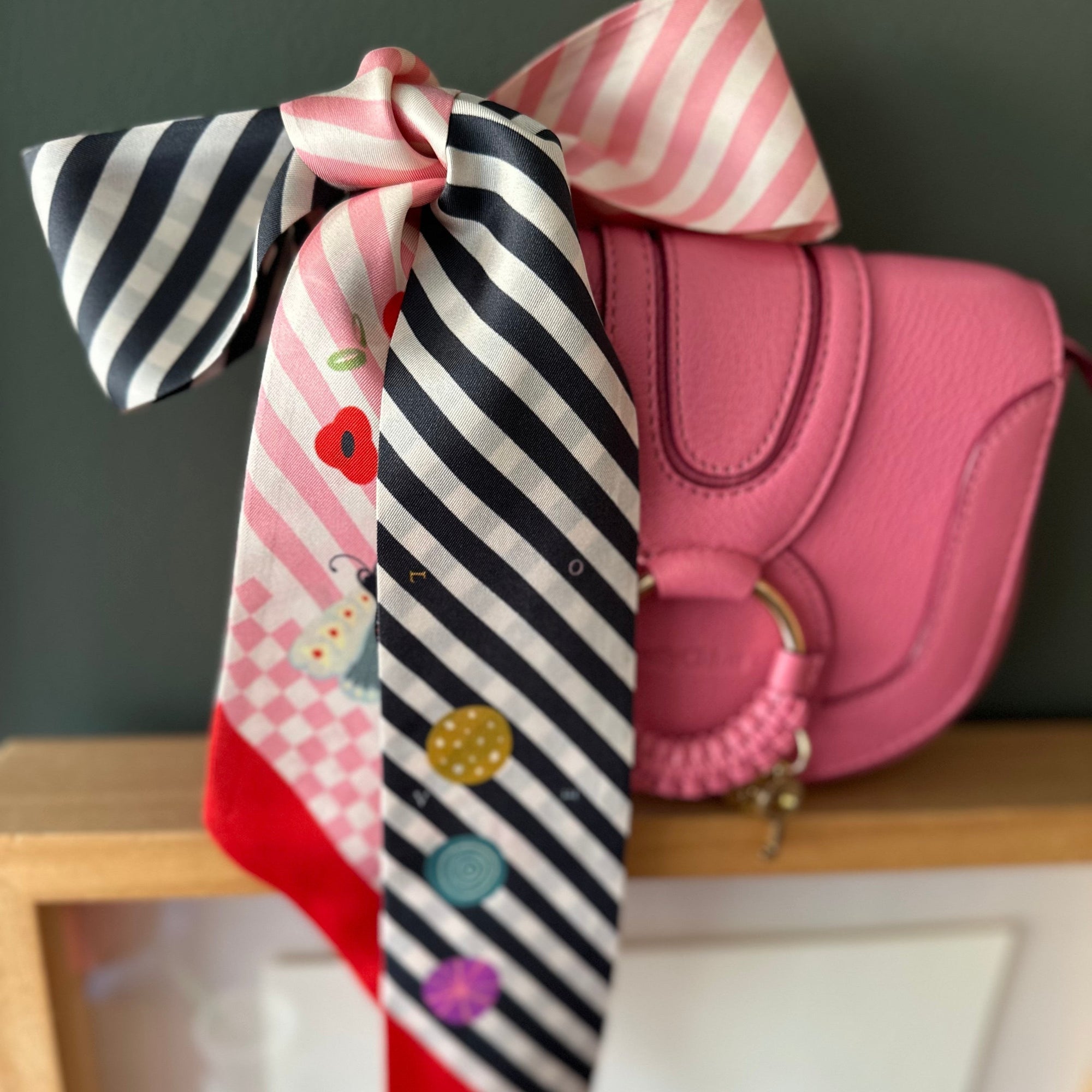 100% ipek, elde yuvarlanmış kenarlar, 6 cm genişlik ve 115 cm uzunlukta, siyah-pembe renk, kelebekler ve cupcake desenli twilly fular.